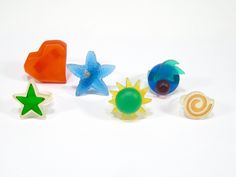 five different colored plastic objects on a white surface with one star and the other sun