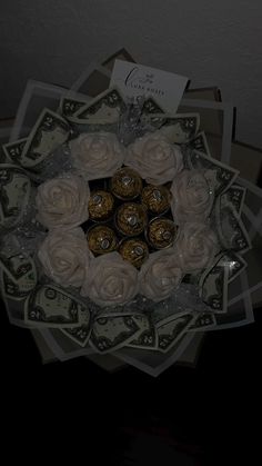 a bunch of money sitting on top of a table next to a vase filled with flowers