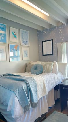 a bedroom with pictures on the wall and a bed in front of a window next to a desk