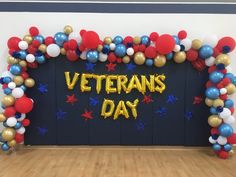 the entrance to a veterans day event with balloons and streamers in gold, red, white and blue colors