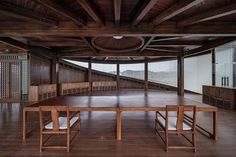 an empty room with tables and benches in the center, surrounded by wood paneling