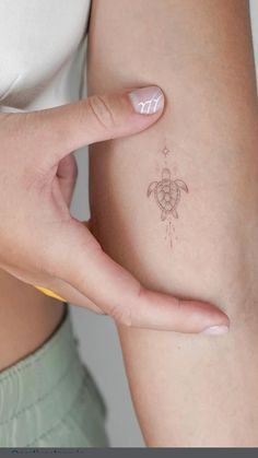 a woman's arm with a small turtle tattoo on the left side of her arm