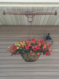 a hanging planter filled with flowers on the side of a garage door next to a light