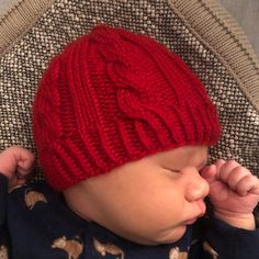 a baby is wearing a red knitted hat