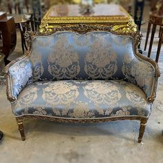 an ornately decorated couch sitting in front of a table with chairs and tables behind it