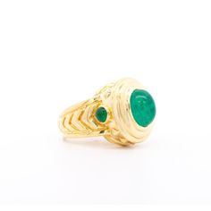 A vintage treasure featuring a stunning 3-carat Colombian emerald cabochon set in 20K yellow gold. The cabochon-cut emerald, exuding rich green hues, commands attention with its captivating sheen.  This ring boasts a unique carved chevron and textured gold design, accentuating its distinguished 20K gold composition. The pointed edges along the ring shank ensure excellent coverage on the finger, ideal for both men and women seeking a statement piece. With its exceptional shine and elevated gold p Yellow Gold Emerald Ring Oval Cabochon, Yellow Gold Emerald Ring With Oval Cabochon, Luxury Yellow Gold Emerald Ring With Oval Cabochon, Formal Emerald Cabochon Ring, Formal Oval Cabochon Emerald Ring, Formal Yellow Gold Cabochons With Bezel Setting, Heirloom Yellow Gold Emerald Cabochon Ring, Classic Gold Emerald Cabochon Ring, Classic Cabochon Emerald Ring For Formal Occasions