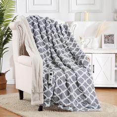 a gray and white blanket sitting on top of a chair next to a potted plant