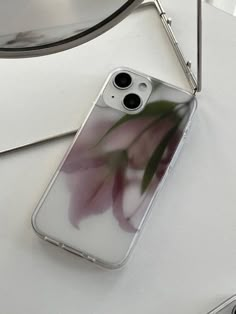 an iphone case with flowers on it sitting next to a camera and some other items