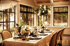 the table is set with white flowers and black place settings for an elegant dinner party