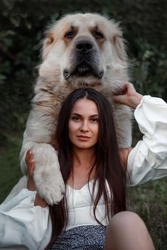 a woman is holding a large dog on her shoulders