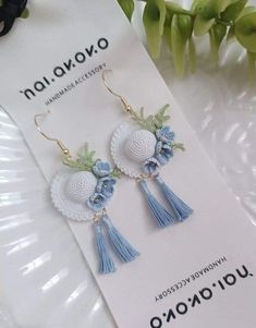 blue tasseled earrings with flowers and beads on them sitting on a white card