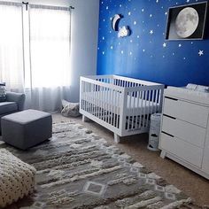 a baby's room decorated in blue and white with stars on the wall, crib, dressers, and bed