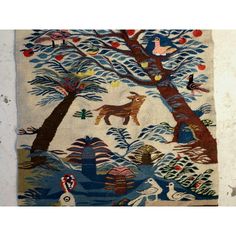 an old tapestry with animals and trees on it's side, hanging from the wall