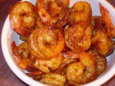 a white bowl filled with cooked shrimp on top of a table