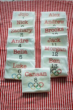 four pieces of cloth with names and numbers on them sitting on a red and white checkered tablecloth