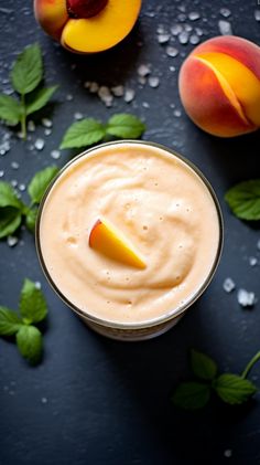 peach smoothie in a glass with two peaches and mint leaves on the side