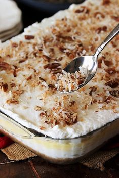 a spoon with some food in it on top of a pan filled with rice and nuts