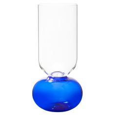 a blue vase sitting on top of a white table next to a glass filled with liquid