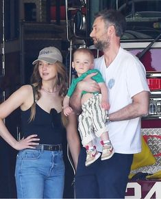 a man, woman and child standing in front of a fire truck