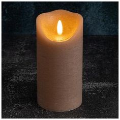 a lit candle sitting on top of a black table next to a dark wall and floor