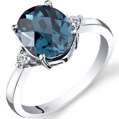 an oval blue topazte and diamond ring with two diamonds on the sides, set in white gold