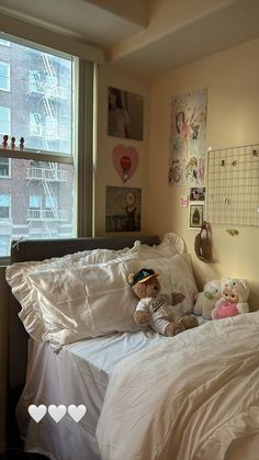 two teddy bears are laying on the bed in front of a window with cityscape