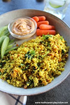 a bowl filled with rice, carrots and celery next to some dipping sauce