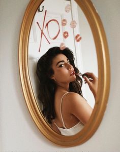 a woman brushing her teeth in front of a mirror with the word xox on it