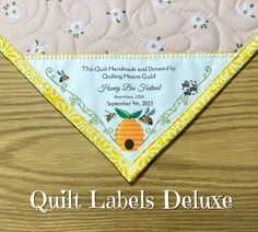 the quilt label is on top of a table cloth with bees and honeycombs