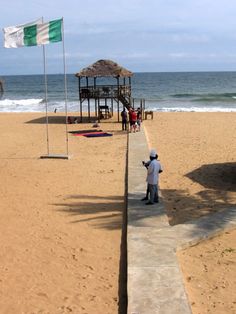 a man standing on top of a sandy beach next to the ocean with an italian flag