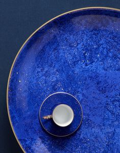 a blue and gold plate with a cup on it