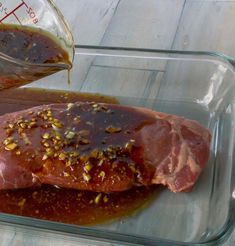 raw meat in a glass dish being poured with ketchup and seasoning mixture