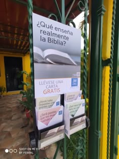 a sign with an open book on it in front of a yellow and green building