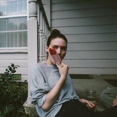 a woman is sitting on the steps with her earphones in her ears and holding something up to her mouth