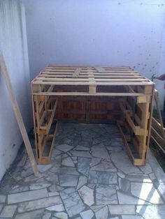 a table made out of wooden pallets sitting on top of a stone floor next to a wall