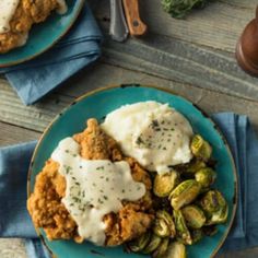 two plates filled with different types of food on top of blue napkins next to silverware