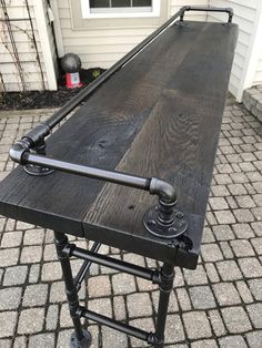 an outdoor picnic table with pipes on the top and legs, sitting in front of a house