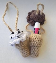 two crocheted items are hanging from twine on a white tablecloth, one has a tube of toothpaste in it and the other is made out of yarn