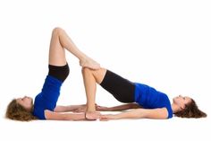 two women are doing yoga exercises on the floor with their legs spread out and one is holding her leg up