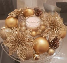 a glass bowl filled with gold ornaments and a candle