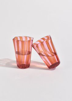 two pink and orange glass cups sitting on top of a white table