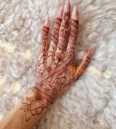 a woman's hand with henna on top of white furnishing area