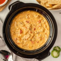 a black crock pot filled with salsa and tortilla chips on the side