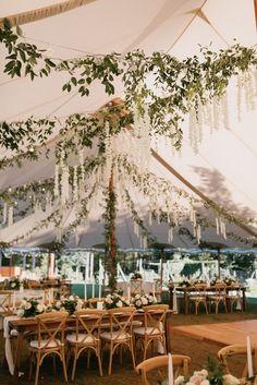 the inside of a tent with tables and chairs set up for an outdoor wedding reception