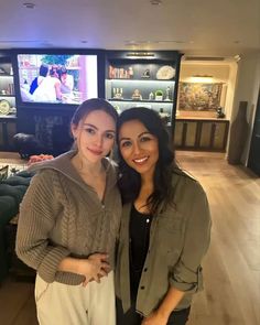 two women standing next to each other in front of a tv