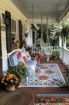 a porch with chairs, rugs and potted plants on the front porch area