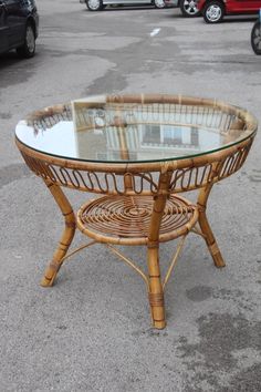 a round glass table sitting on top of a parking lot next to a parked car