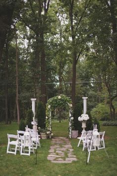 an outdoor ceremony set up with white chairs