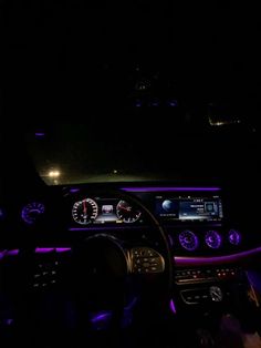 the interior of a car is lit up with purple lights and steering wheel controls,