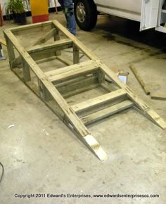 a white van parked in a garage next to a wooden frame with steps on it